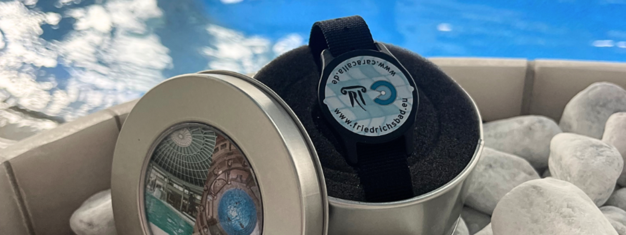 Silberne Metalldose mit VIP-Chip-Armband vor dem Thermalbecken, dekoriert mit weißen Steinen